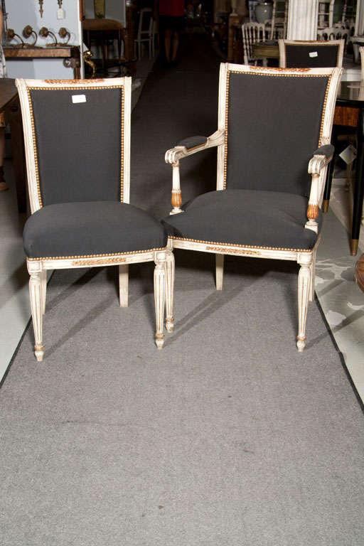 A pair of arm chairs, circa 1940s in the taste of French Directoire, each distress-painted and parcel-gilt frame upholstered in black fabric. Stamped Jansen.